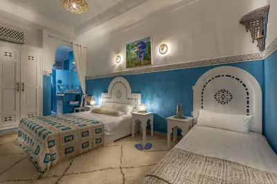 a bedroom with two beds and a blue wall at Astra Damus Hotel in Marrakech