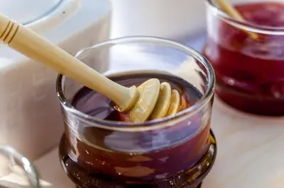 a glass jar of jam with a wooden stick in it at Riad Dar Yema in Marrakech