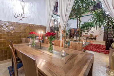 a dining room with a wooden table with red flowers at Riad Dar Yema in Marrakech