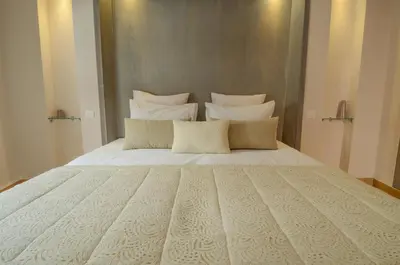 a large bed with white sheets and pillows at Riad Ayni in Marrakech
