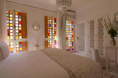 a bedroom with a white bed and colorful windows at Riad Andallaspa in Marrakech
