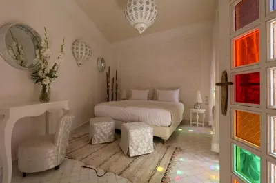 a bedroom with a bed and a chair in it at Riad Andallaspa in Marrakech