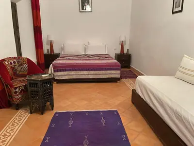 a bedroom with two beds and a chair and a purple rug at Riad Safia in Marrakech