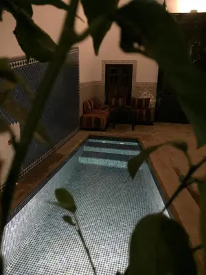 a swimming pool in a living room with a chair and a couch at Riad Safia in Marrakech