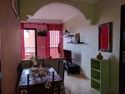 a dining room with a table and a room with red windows at Appartement Marrakech in Marrakech