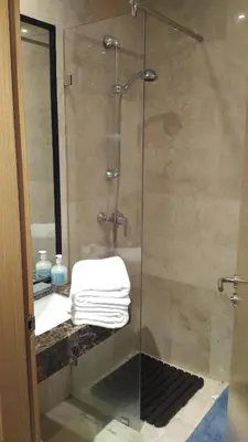 a shower with a glass door with a sink and towels at Appartement Privé au Vizir Center Marrakech in Marrakech
