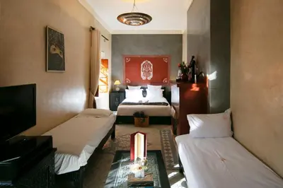 a hotel room with two beds and a television at Riad Alili in Marrakech