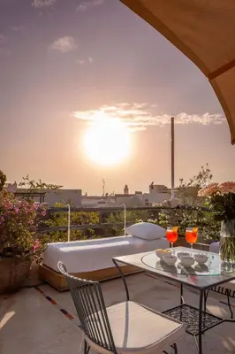 a patio with a table and chairs and the sunset at Riad Azahar in Marrakech