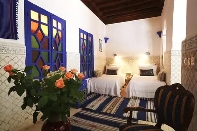 a room with two beds and a vase with flowers at Riad Merstane Marrakech in Marrakech