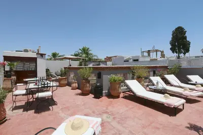 a patio with a bunch of lounge chairs and tables at Riad Merstane Marrakech in Marrakech