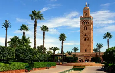 a clock tower with palm trees in front of a building at Appartement Wassim - Gueliz in Marrakech