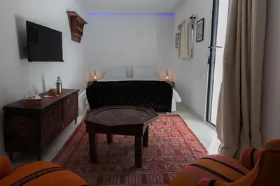 a bedroom with a bed and a table and a tv at Riad Zebrakaro in Marrakech