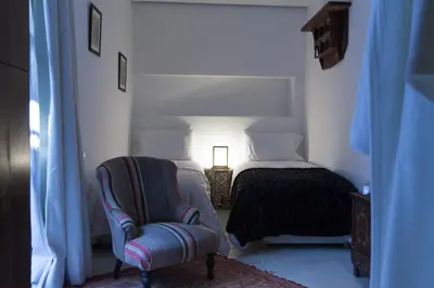 a bedroom with a chair and a bed with a lamp at Riad Zebrakaro in Marrakech