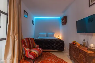 a bedroom with a bed and a chair with a blue light at Riad Zebrakaro in Marrakech