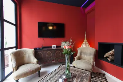a red living room with two chairs and a fireplace at Riad Zebrakaro in Marrakech