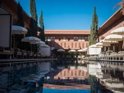 a swimming pool with umbrellas and a building at Kenzi Club Agdal Medina - All Inclusive in Marrakech