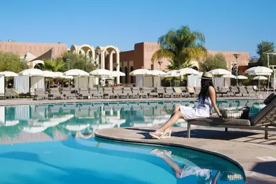 a woman sitting on a bench next to a swimming pool at Kenzi Club Agdal Medina - All Inclusive in Marrakech