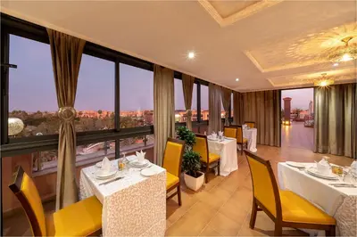 a restaurant with tables and chairs and a view of the city at Palm Menara Hotel Marrakech in Marrakech