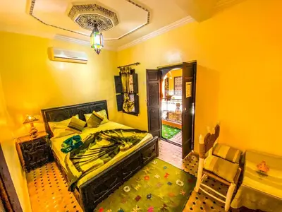a yellow bedroom with a bed and a chair at Riad Salma Restaurant Spa in Marrakech