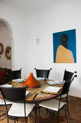 a dining room with a table with chairs and a painting at Riad Al Tainam in Marrakech