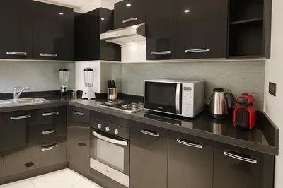 a kitchen with black cabinets and a microwave and a sink at Sabor Apartments Anas Majorelle in Marrakech