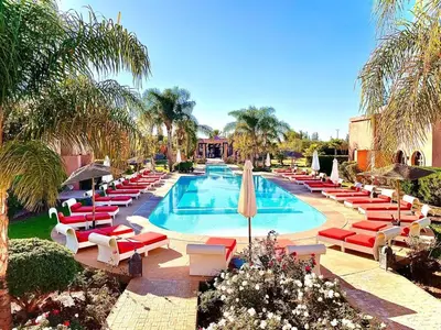 a swimming pool with red and white lounge chairs and a swimming pool at Les Résidences Du Domaine in Marrakech