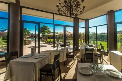 a restaurant with tables and chairs and large windows at Les Résidences Du Domaine in Marrakech