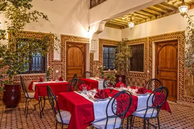 a dining room with tables and chairs with red tablecloths at Hostel Amour d'auberge in Marrakech