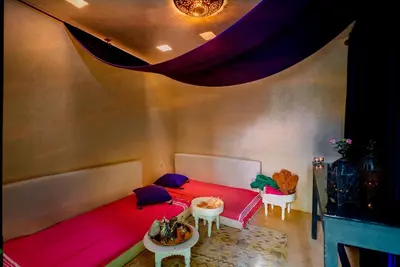 a bedroom with a red bed and two tables at Riad Ines Home in Marrakech