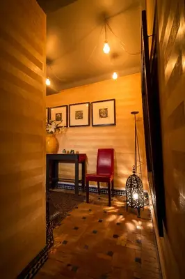 a hallway with a table and a red chair at Riad Ines Home in Marrakech