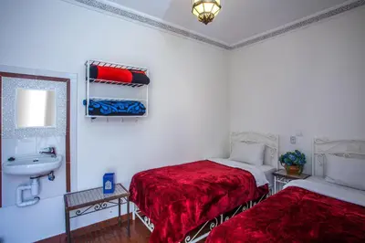 a bedroom with two beds and a sink and a mirror at Hotel Zitoune in Marrakech
