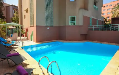 a large swimming pool with chairs next to a building at Appart-Hotel Amina Resort & Spa in Marrakech