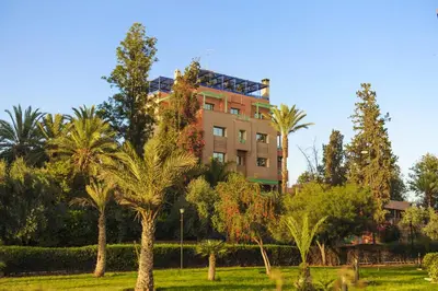 a building with palm trees in front of it at Appart-Hotel Amina Resort & Spa in Marrakech