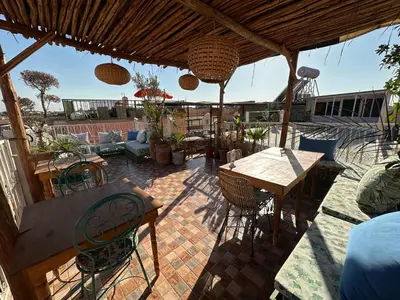 a patio with a table and chairs under a roof at Riad Green Vines in Marrakech