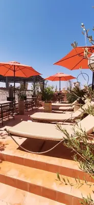 a row of tables and umbrellas with tables and chairs at Dar Andamaure in Marrakech