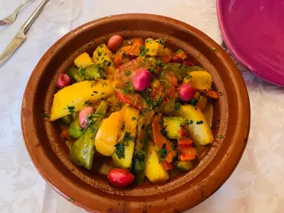 a brown bowl of food with vegetables on a table at Riad Jardin Des Rêves in Marrakech