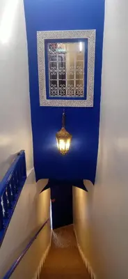a hallway with a blue wall with a light on it at Riad Tifor in Marrakech