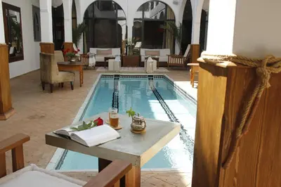 a swimming pool with a table and a book on a table sidx sidx at Riad Utopia Suites And Spa in Marrakech