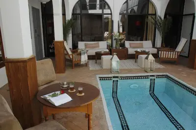a living room with a large swimming pool with a table and chairs at Riad Utopia Suites And Spa in Marrakech