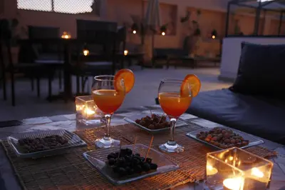 a table with two glasses and plates of fruit and candles at Riad Utopia Suites And Spa in Marrakech