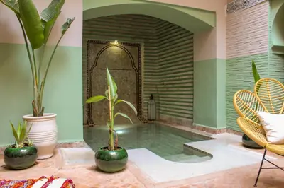 a pool in a room with plants and chairs at Riad Amra in Marrakech