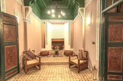 a living room with a fireplace and two chairs at Le Medina Privilège Riad & Spa in Marrakech