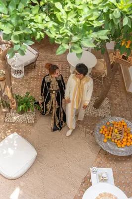 two women are sitting on a floor with oranges at Riad Les Orangers D'alilia in Marrakech