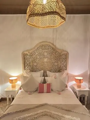 a bedroom with a large bed with pillows and a chandelier at Riad Les Orangers D'alilia in Marrakech