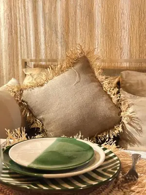 a green plate on a table with a pillow at Riad Les Orangers D'alilia in Marrakech