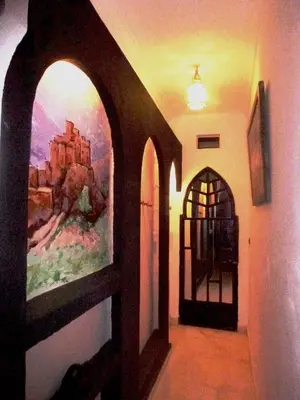 a hallway with a painting on the wall and a door at Ryad Laârouss Family in Marrakech