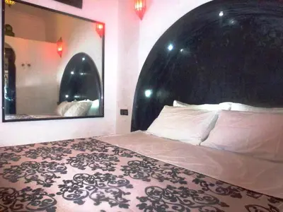a bedroom with a large bed and a mirror at Ryad Laârouss Family in Marrakech