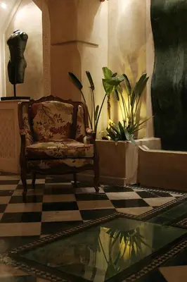 a room with a chair and plants on a checkered floor at Riad Moullaoud in Marrakech