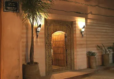 a door in a building with a palm tree in front at Riad Moullaoud in Marrakech