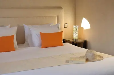 a bed with orange and white pillows and a book at Riad Le Jardin d'Abdou in Marrakech